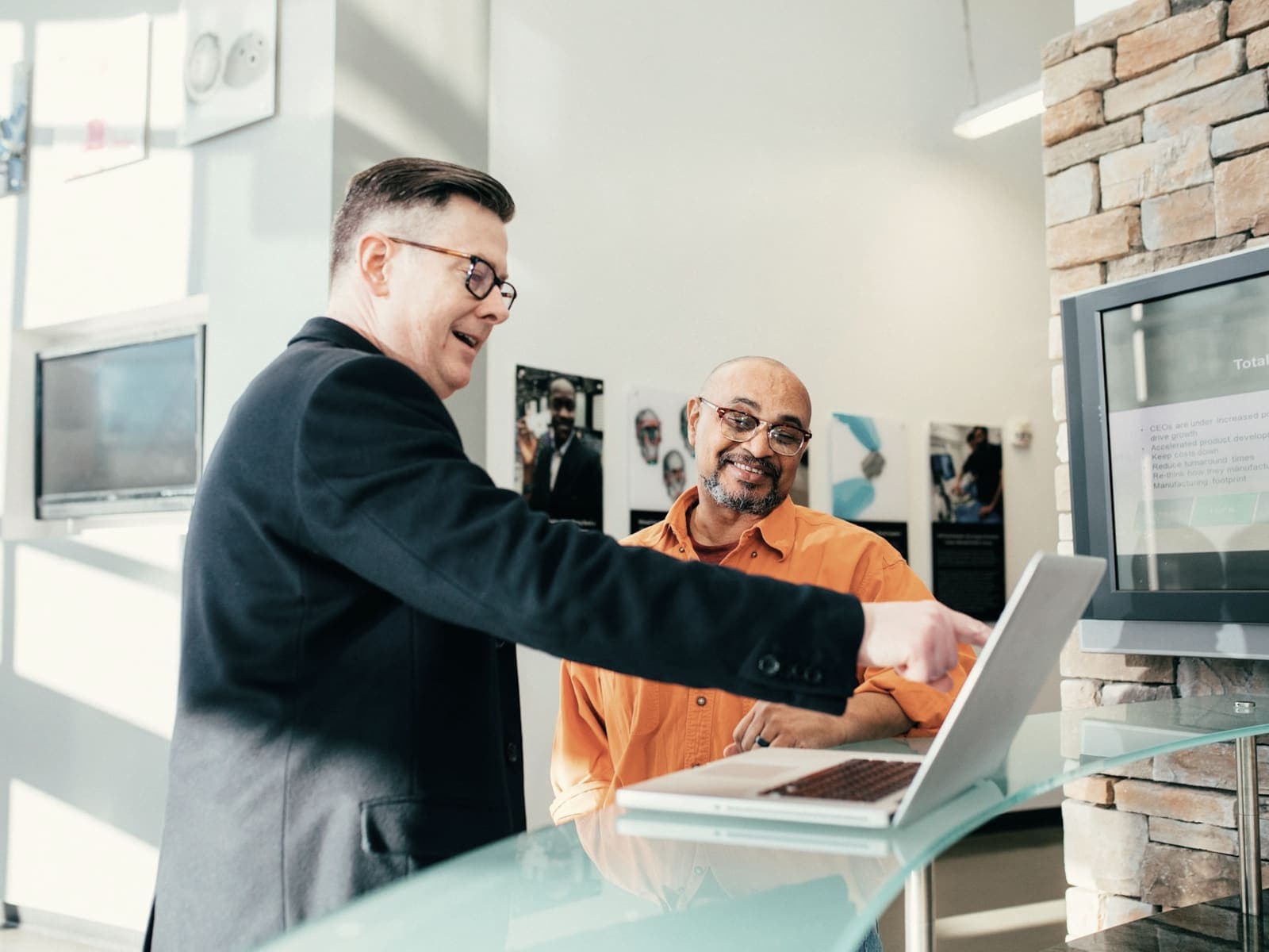 Two people looking at a laptop together, one pointing at the screen