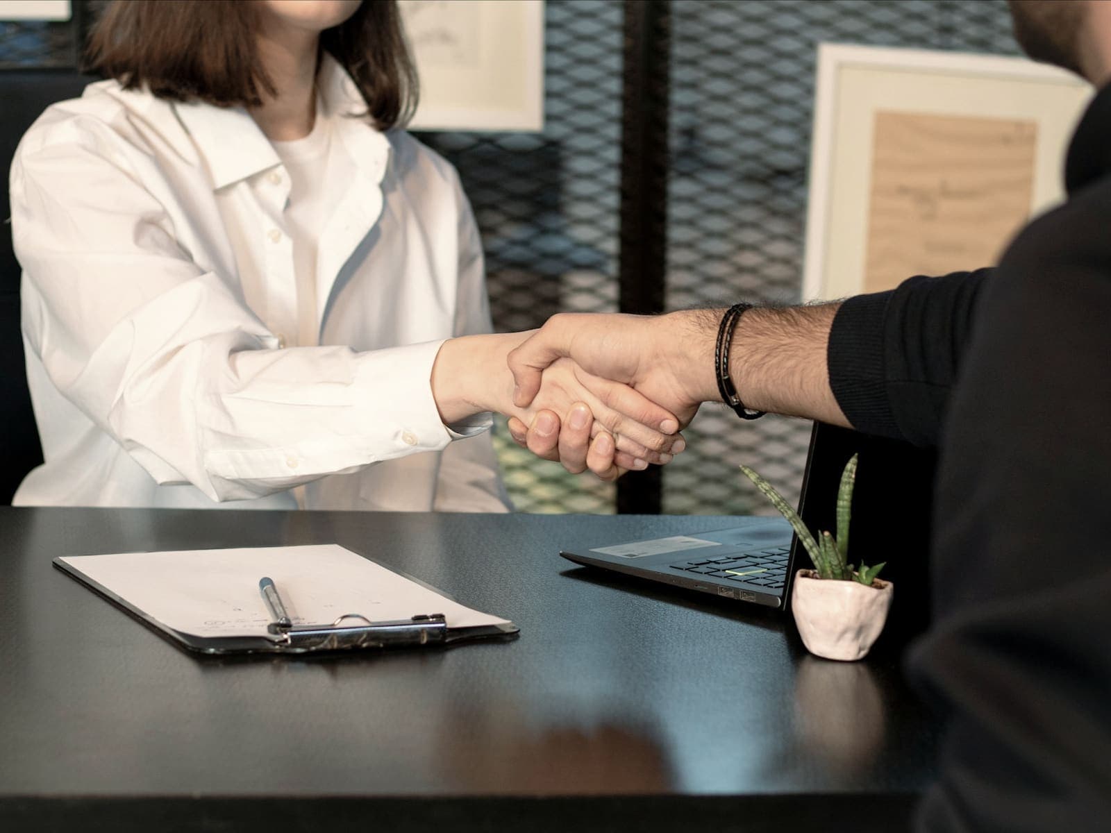 Two people shaking hands across a desk