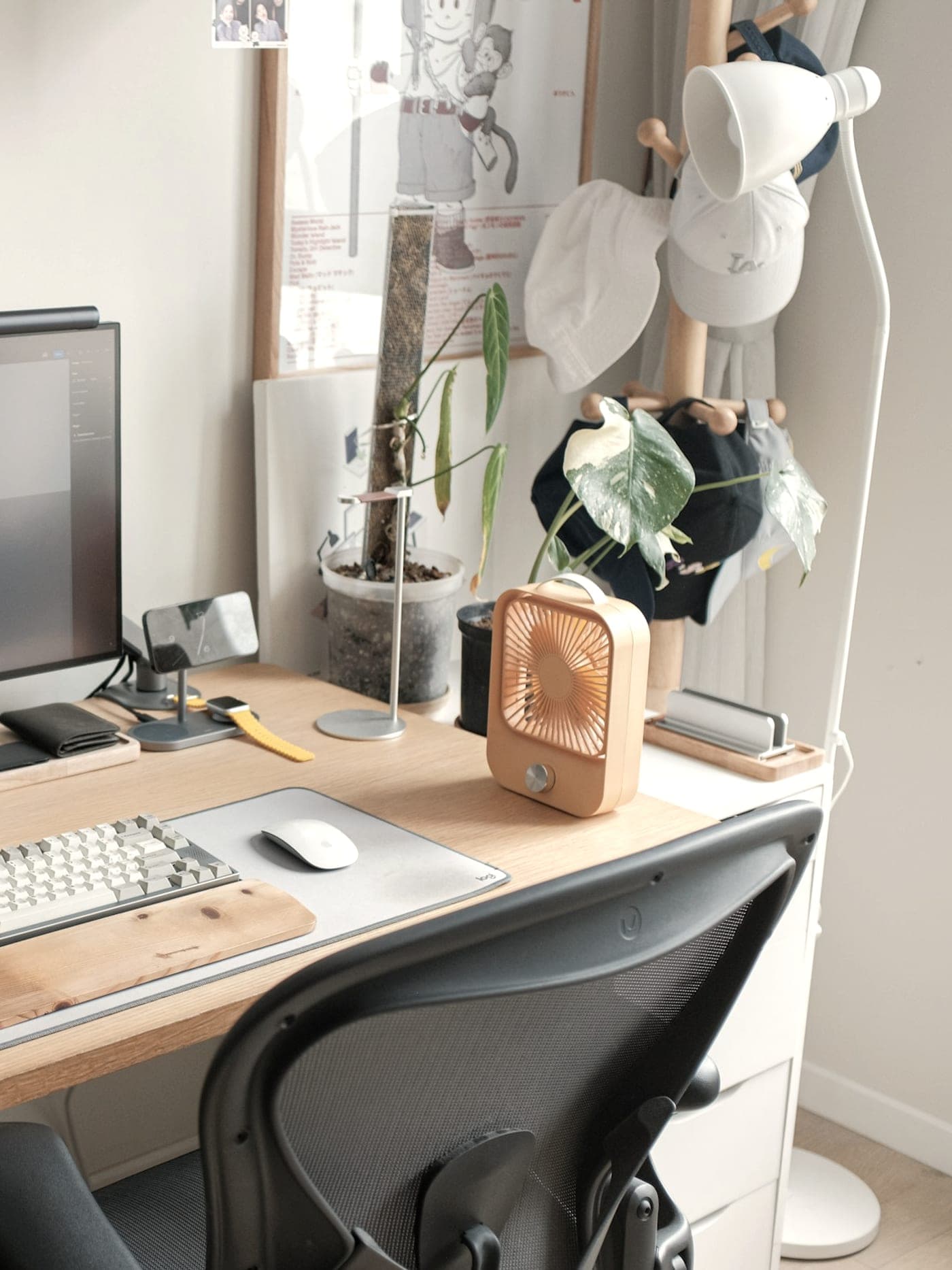 A tidy, lived-in desk with a laptop, a monitor and a keyboard by a window