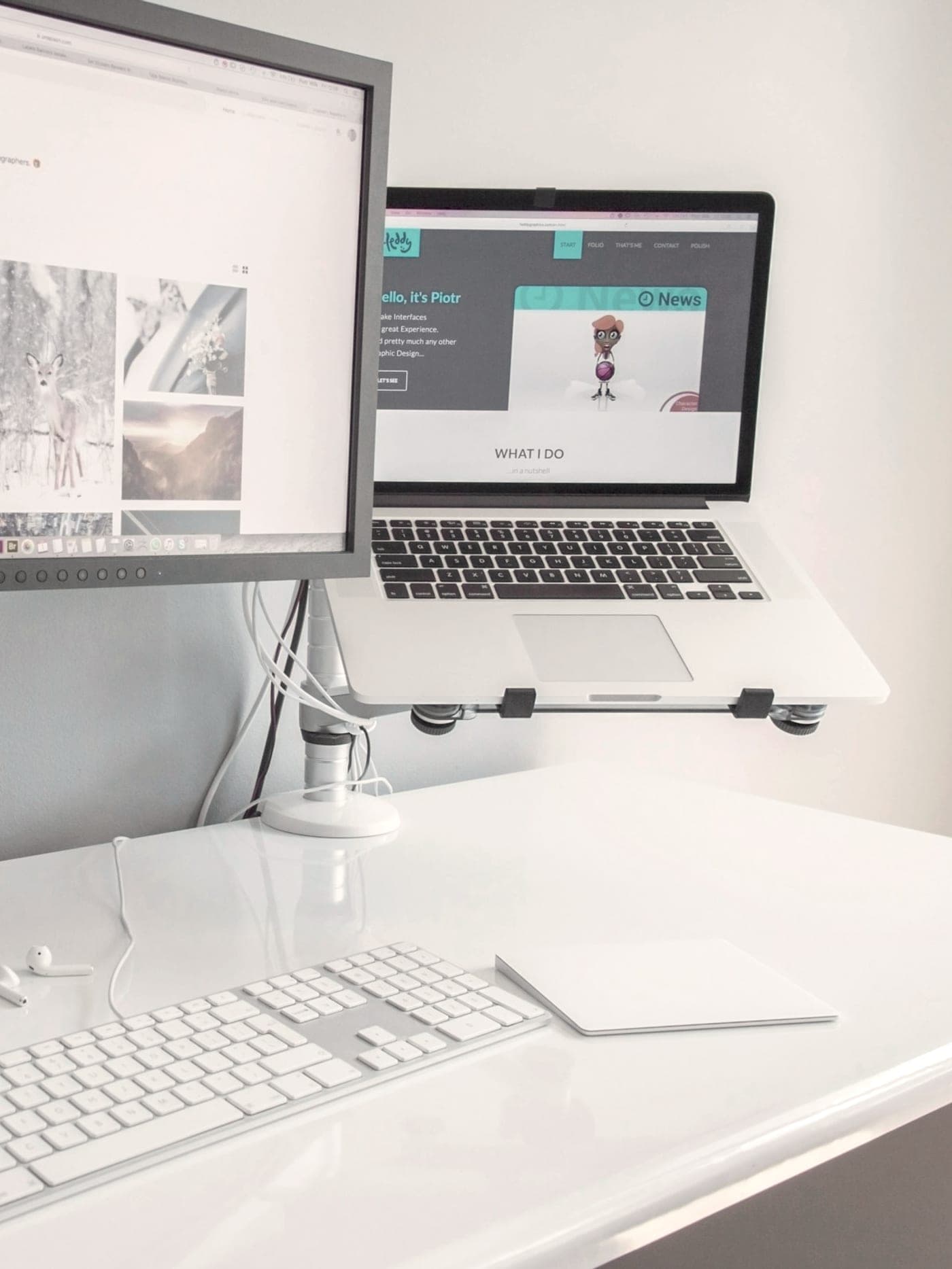 A monitor and a laptop on a white desk, both showing a developer portfolio site