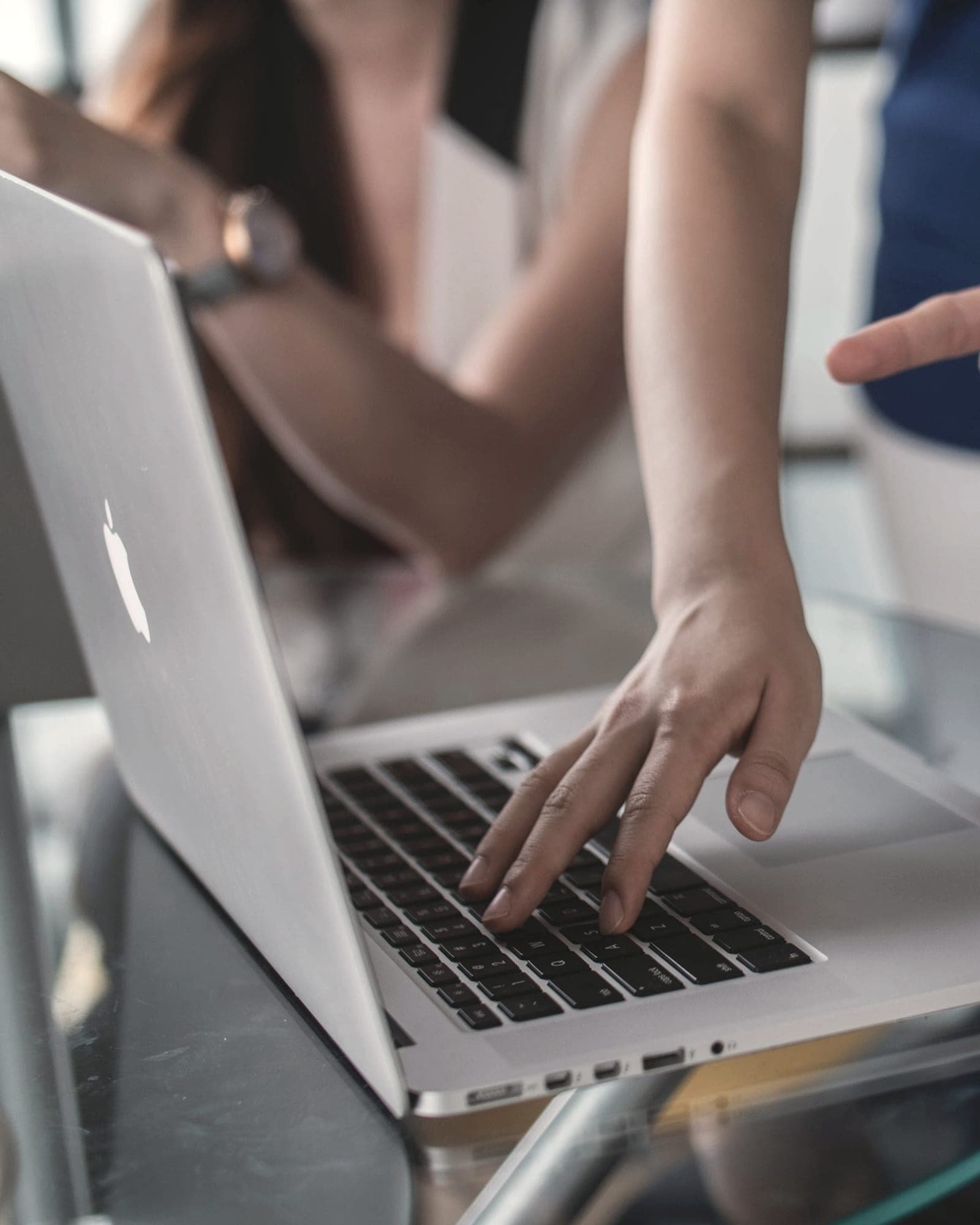 Several hands around one laptop as a small team works through something together