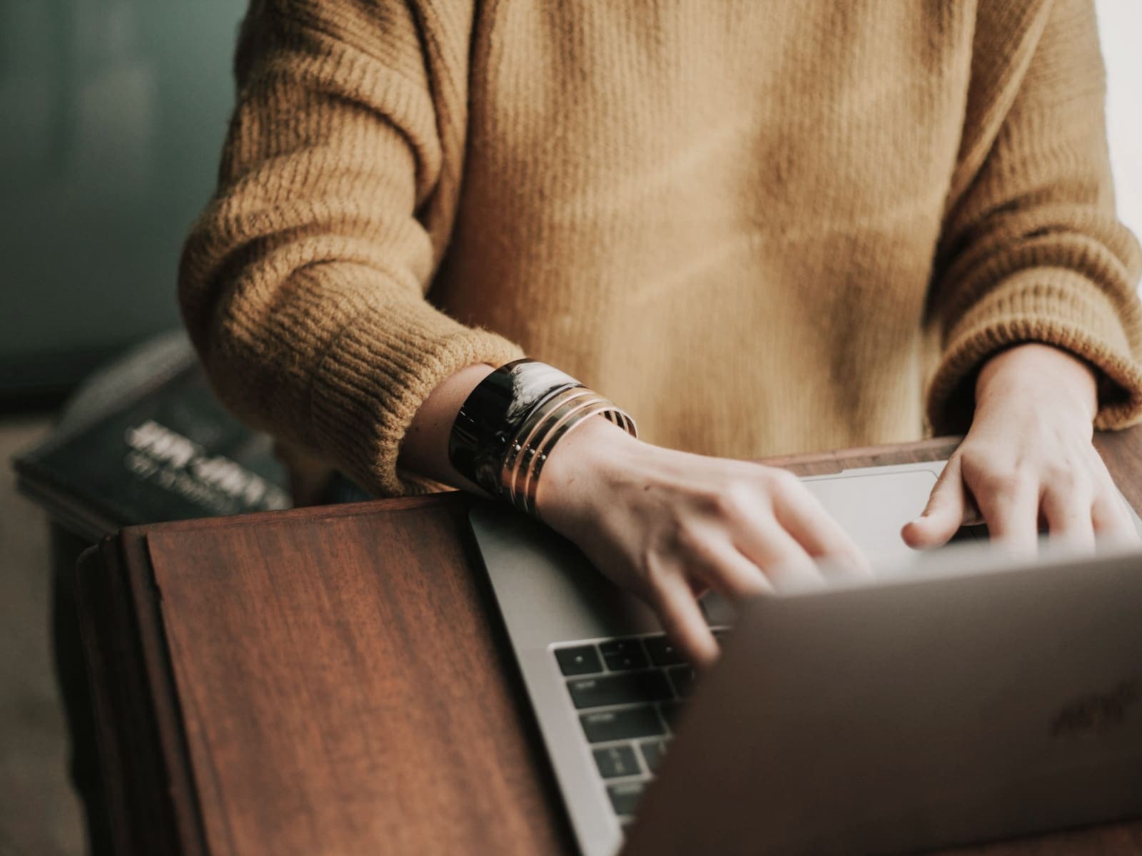 Hands typing on a laptop at a wooden desk