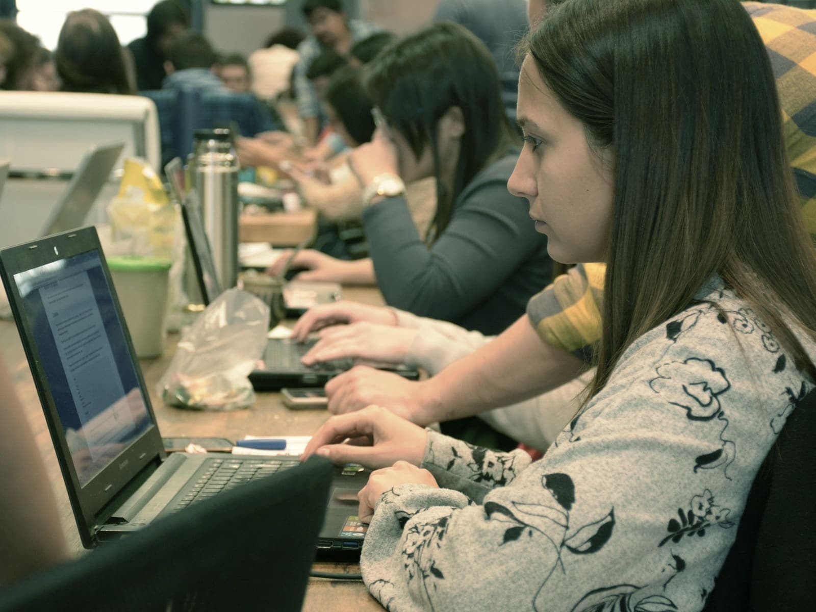 A developer reading through a list on a laptop in a busy shared office